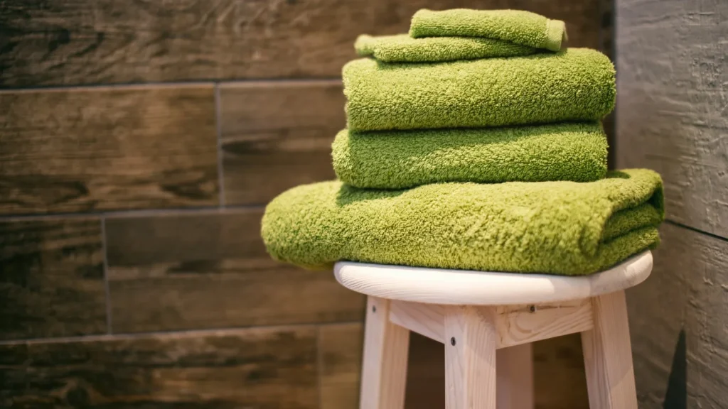 Pile de serviettes éponge pliées sur un tabouret en bois dans une salle de bains